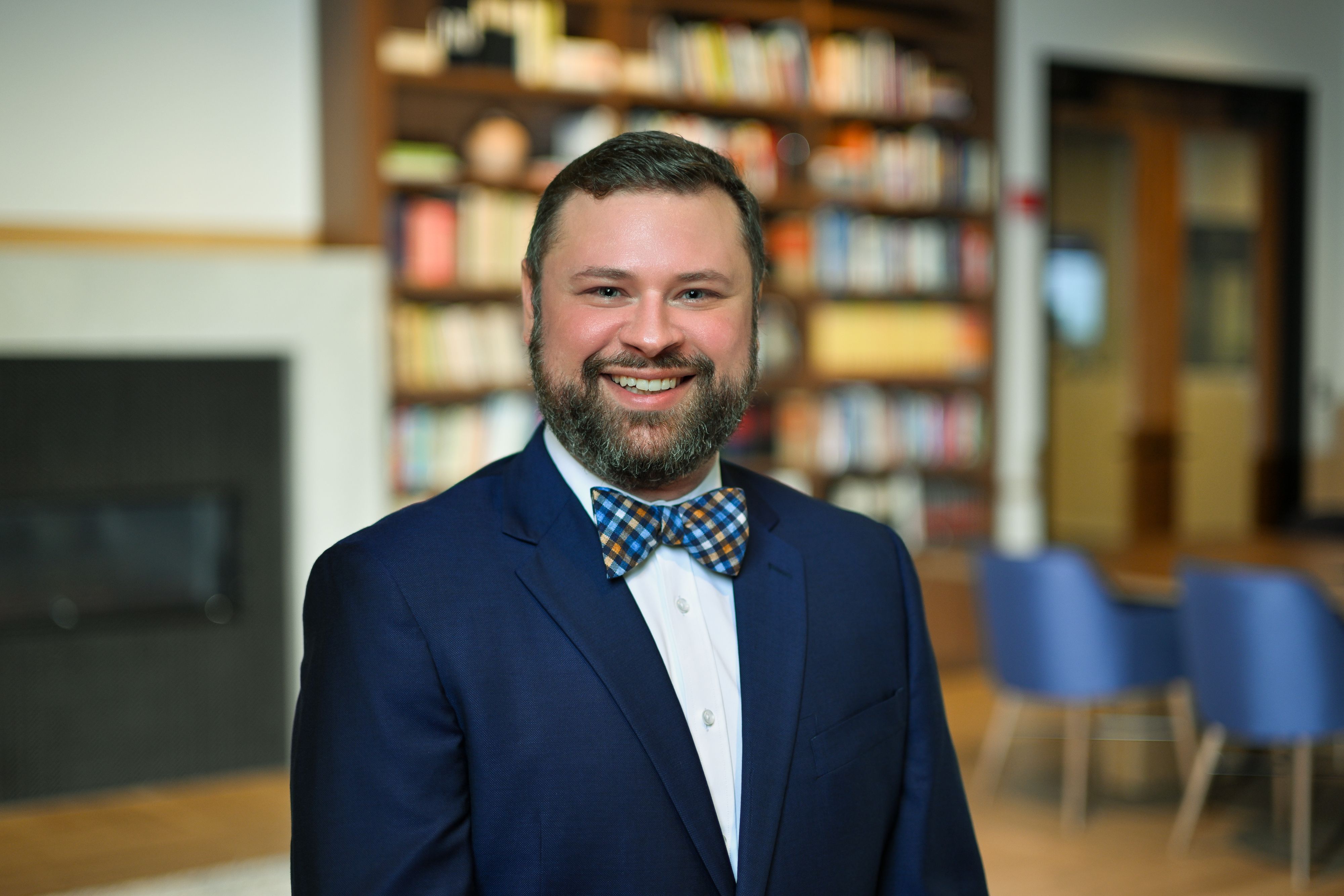 Ethan Hussong smiling in a library, wearing a navy suit and patterned bow tie.